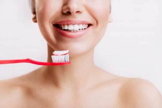 girl with sincere smile makes morning routine brushes her teeth isolated wall min
