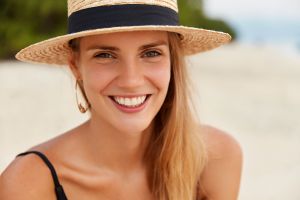 close up shot attractive female has warm eyes broad smile with white even teeth wears beach hat recreate luxurious resort summer travelling tourism concept woman tropical island min